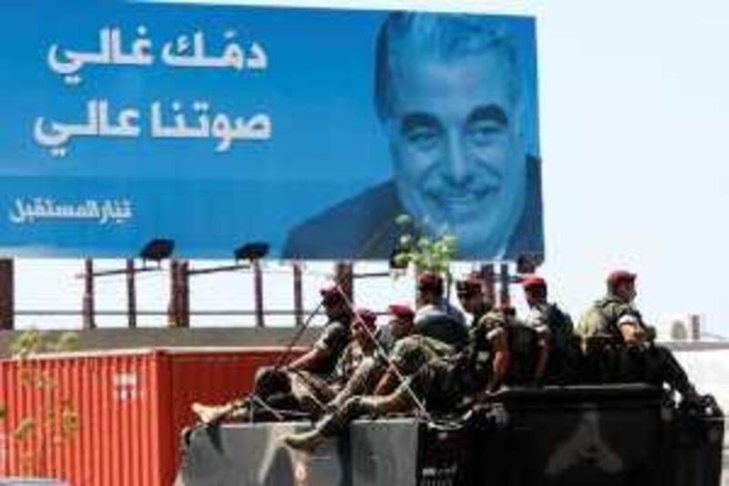 Members of a special commando unit of the Lebanese army sit on their armored personnel carrier during a patrol ahead of Sunday's parliamentary elections, as they pass in front of a poster of slain former Lebanese prime minister Rafik Hariri with an Arabic words read:" Your blood is precious, and our voice is high," in Beirut, Lebanon, on Saturday, June 6, 2009. Lebanese voters face a stark choice Sunday between renewing the mandate of a pro-Western coalition or handing power to an Iranian-backed  Hezbollah-led alliance that could bring international isolation and new conflict with Israel upon the small, tumultuous country.   (AP Photo/Hussein Malla) *** Local Caption ***  BEI110_Mideast_Lebanon_Elections.jpg