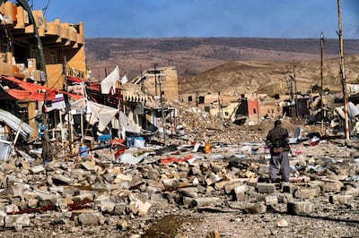 SINJAR, REGIONAL GOVERNMENT OF KURDISTAN, IRAQ - 2015: A civilian walks among the ruins of the devastated town of Sinjar, after its liberation.  The town was liberated from ISIS on November 13th, 2015 by the Peshmerga forces of Iraqi Kurdistan. The Kurdish word "Peshmerga" is used to refer to those who are part of Iraqi Kurdistan's armed forces. It means "u201cone who confronts death," or "will fight to the death."u201d The capture of Sinjar by the Islamic State on August 3rd, 2014 was very violent. Over 35,000 Yazidi Kurd inhabitants attempted to flee into the nearby mountains. Those who could not escape were killed and the Yazidi women abducted by ISIS were sold or used as sex slaves. (Photo by Reza/Getty Images)