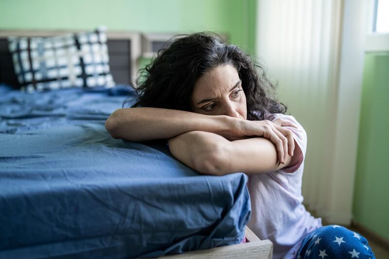 Mid adult woman sitting home alone, worried.