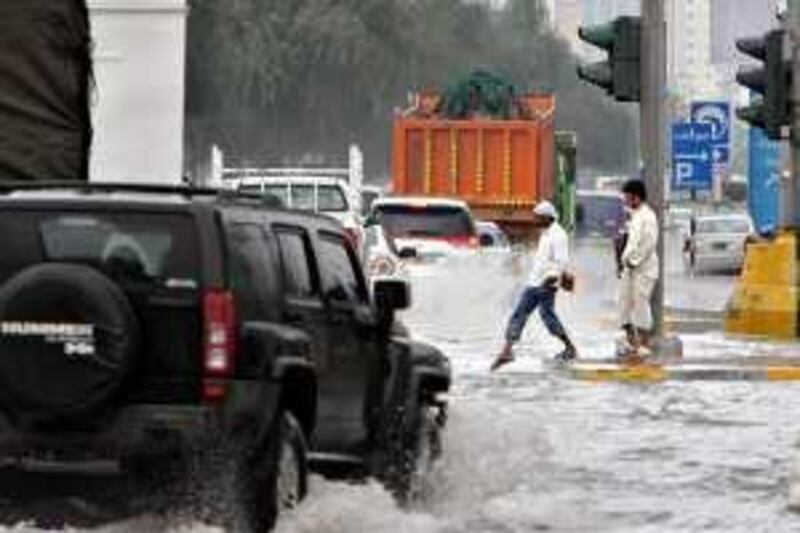 United Arab Emirates - Abu Dhabi - Dec 13 - 2009 : People try to cross a flooded street in the old airport road. ( Jaime Puebla / The National ) *** Local Caption ***  JP Flooding 09.jpg