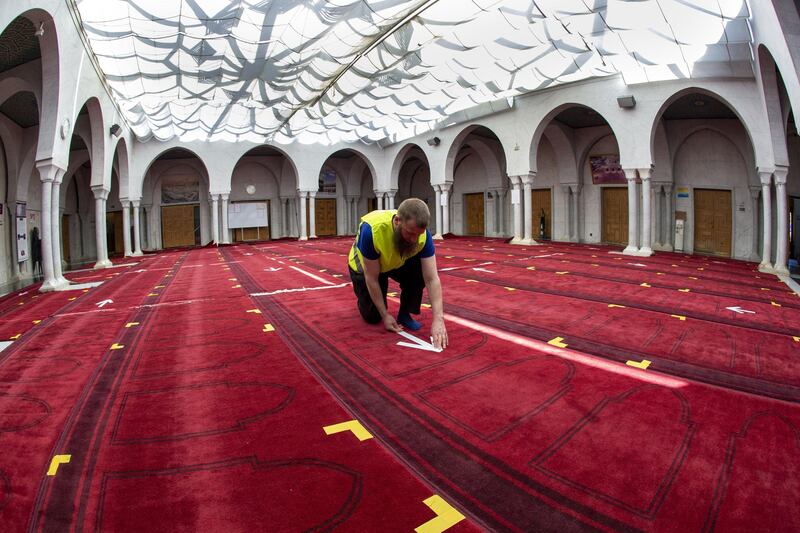 A member of staff at the Geneva Mosque installs markings on the floor as a precaution against the spread of the coronavirus.  EPA