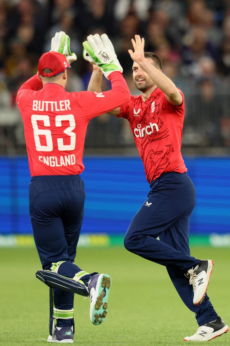 England captain Jos Buttler celebrates with Mark Wood after the dismissal of Australia batter Tim David for a duck. AFP