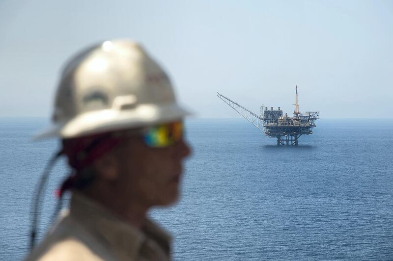 A picture taken on July 30, 2015 shows a worker from the Israeli gas-drill Tamar platform in front of the Mari-B platform in the Mediterranean Sea off the coast of Israel. The Tamar platform is located south-west off Tel Aviv, and some 150 kilometres south of the actual reservoir, from which it receives the gas via an underwater pipeline, before processing it. Israeli Prime Minister Benjamin Netanyahu announced on August 13, 2015 a major deal between his government and a consortium including US firm Noble Energy on natural gas production in the Mediterranean Sea. AFP PHOTO / AHIKAM SERI (Photo by AHIKAM SERI / AFP)