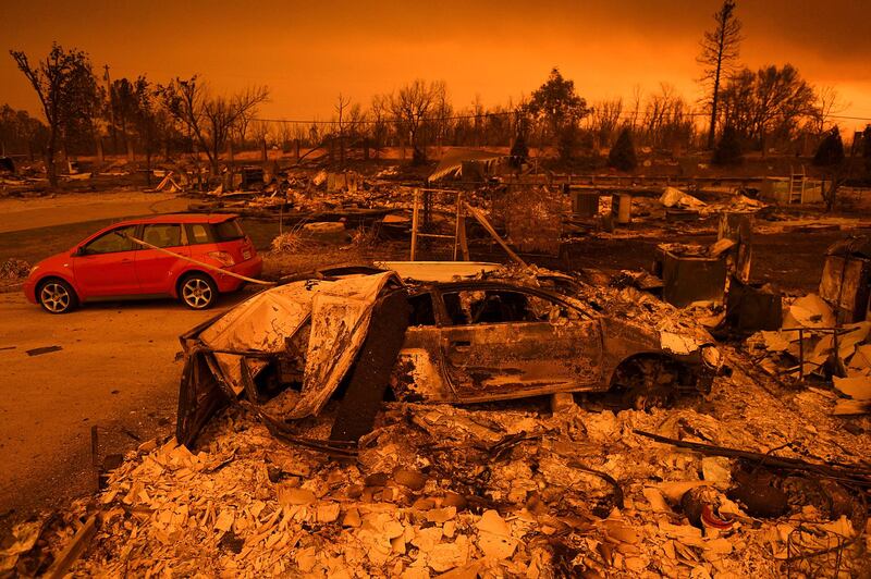Two vehicles that endured the Carr Fire, one with minor cosmetic damage and one destroyed, rest among leveled homes in the Lake Keswick Estates area of Redding, California.  AP Photo / Noah Berger