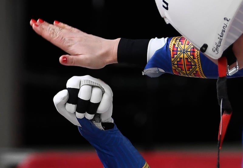 The gloved hand of Team Romania Cosmin Atodiresei congratulations with the hand with painted red nails of female team member Raluca Stramaturaru as they compete in the Luge Team Relay competition. Filip Singer / EPA