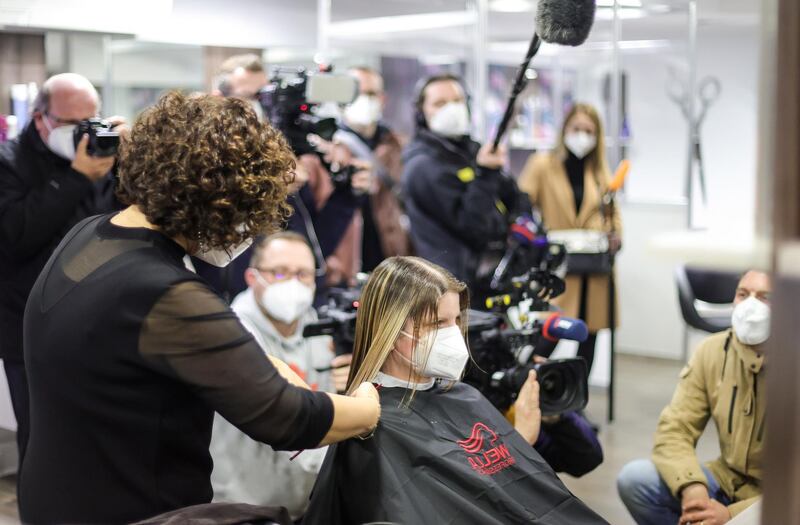 Hairdresser Sadiye Kisin cuts the hair of her first customer as members of the press gather around just after midnight in Duisburg. EPA