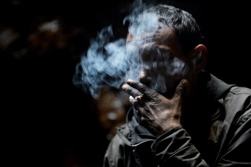 A coal miner smokes a cigarette while taking a break near Rimbay village in the Indian state of Meghalaya. Roberto Schmidt / AFP Photo

