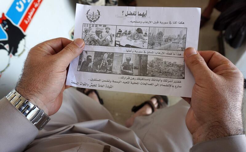 A Syrian man holds a leaflet stamped with the government forces' seal and dropped by helicopters flying over the Syrian city of Saraqib, southwest of Aleppo on August 9, 2018 reading in Arabic: "Which do you prefer? This was Syria before terrorism and its militiamen, and this is what armed terrorism has one to Syria and its people. The fate of your family, children, and future depend on your decision. Quickly join the local reconciliations to return the smile and guarantee the future." - Syrian government forces on August 9 shelled rebel and jihadist positions in the northwestern province of Idlib, the largest chunk of territory still in rebel hands, and dropped leaflets warning of an impending assault and urging surrender. (Photo by OMAR HAJ KADOUR / AFP)