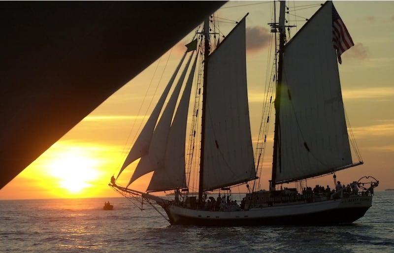 11/02 -- KEY WEST, FLA -- A sloop?, dwarfed by the hull of an snchored cruise ship, sails into the sunset off Mallory Square. Hundreds of tourists flock to the square to watch the sun set. DIGITAL IMAGE -- JIM RANKIN/THE TORONTO STAR (Photo by Jim Rankin/Toronto Star via Getty Images)