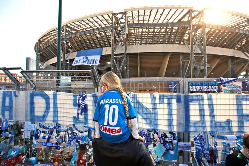 A girl looks at the memorabilia placed outside the San Paolo stadium in Naples in memory of Diego Maradona. AP