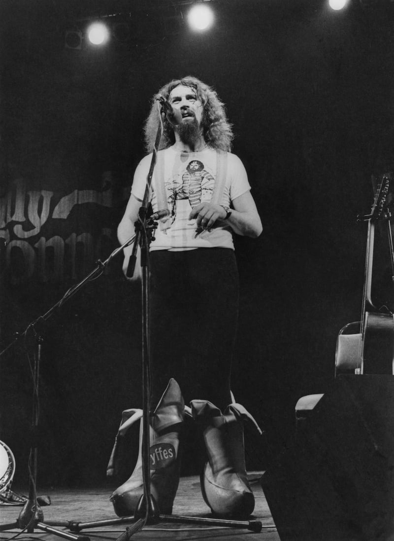 Scottish comedian Billy Connolly performing on stage in a pair of outsize, banana-shaped boots, 7th July 1977.  (Photo by Evening Standard/Hulton Archive/Getty Images)