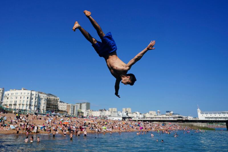 A person cools off by jumping into the sea at Brighton beach, England.