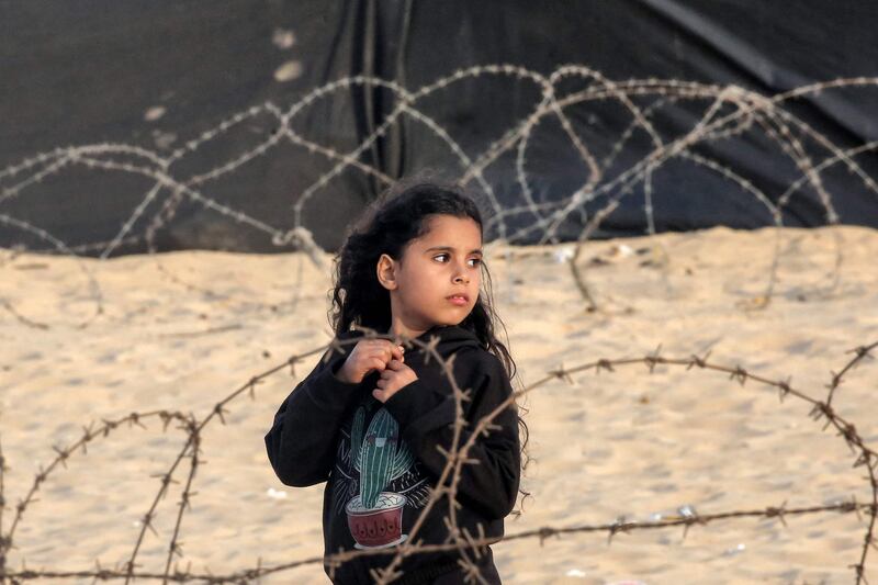 A girl stands between barbed wire at a camp housing displaced Palestinians in Rafah in the southern Gaza Strip. AFP