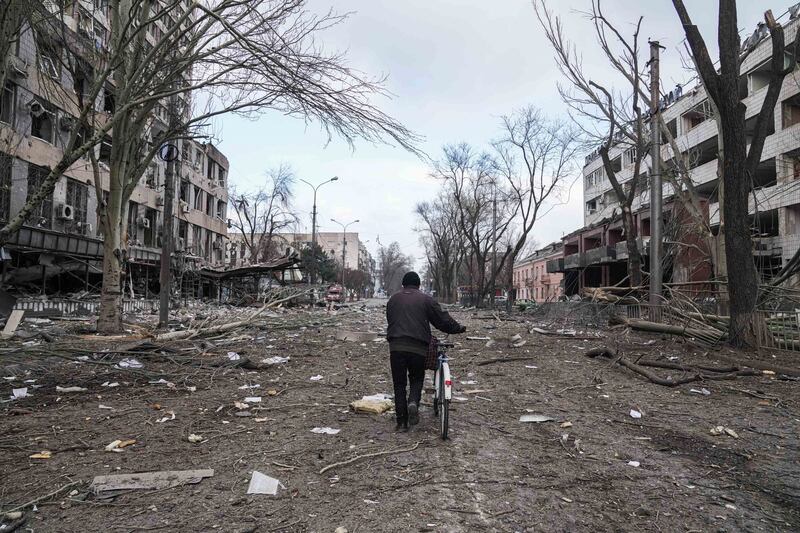 A man pushes a bicycle along a destroyed street in Mariupol. AP Photo