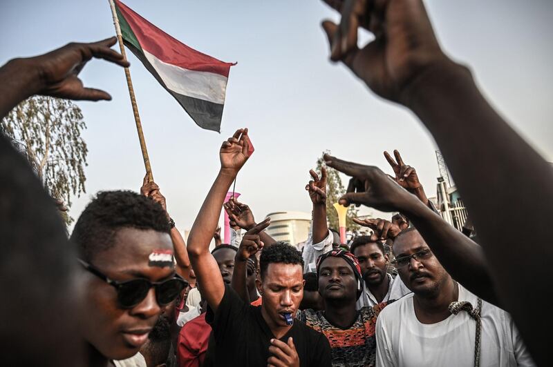 Sudanese protesters wave national flags and shout slogans during a protest outside the army headquarters in the capital Khartoum on April 19, 2019.  Protest leaders on April 19, 2019 announced plans to unveil a civilian ruling body to replace the current transitional military council as crowds of demonstrators kept up the pressure outside army headquarters and Washington said it will send an envoy to encourage the transition.  / AFP / OZAN KOSE
