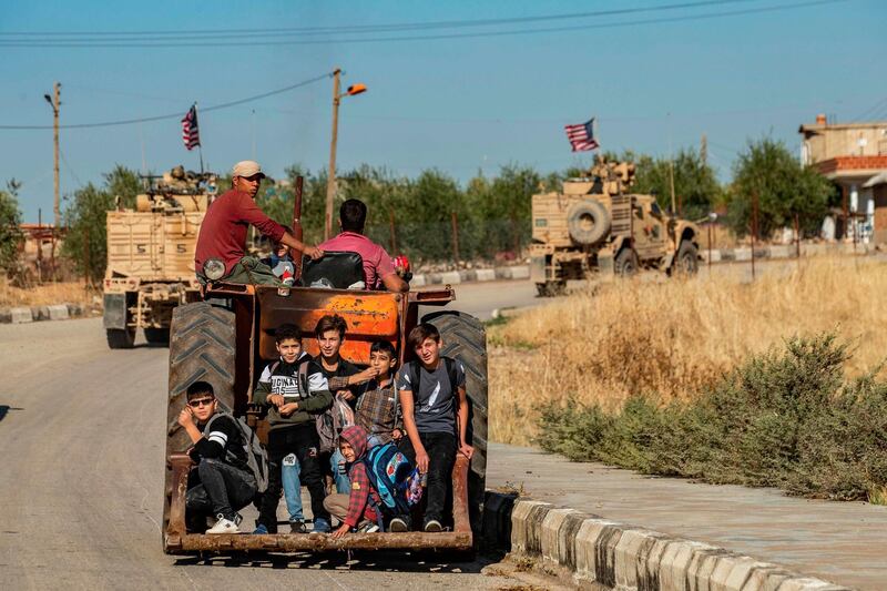 A convoy of US armoured vehicles (background) patrols the village of Ein Diwar in Syria's northeastern Hasakeh province. AFP