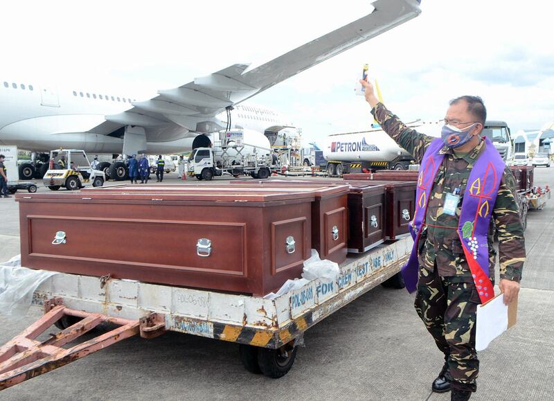 A military priest wearing a face mask blesses the repatriated remains of Filipino workers at Manila's international airport, Philippines.  EPA