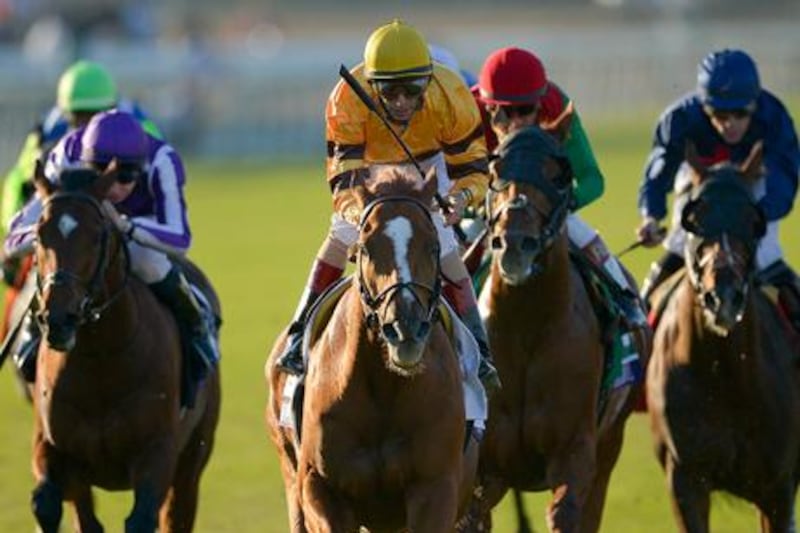 Jockey John Velazquez, centre, stands up as he rides Wise Dan across the finishing line at the Breeders' Cup Mile.