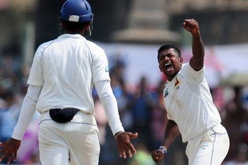 Sri Lankan spinner Rangana Herath (R) celebrates after dismissing England's Graeme Swann (unseen) during the fourth day of the opening Test Match between Sri Lanka and England at the Galle International Stadium in Galle on March 29, 2012. AFP PHOTO/LAKRUWAN WANNIARACHCHI

