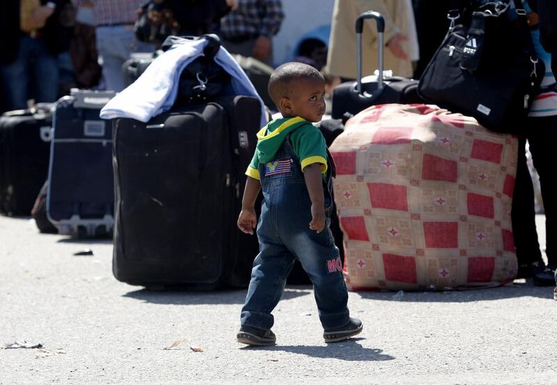 A young boy walks beside some luggage as people wait to cross into to Egypt, at the border in Rafah, Gaza Strip. Hatem Moussa / AP Photo