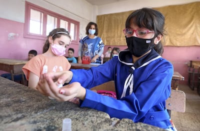 Syrian pupils, some wearing protective face masks, disinfect their hands in class in the capital Damascus on September 13, 2020, during the first day of the school year. (Photo by LOUAI BESHARA / AFP)