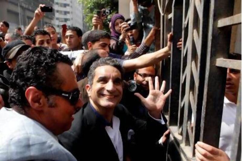 Egyptian television satirist Bassem Youssef, who has come to be known as Egypt's Jon Stewart, waves to his supporters as he enters Egypt's state prosecutors office to face accusations of insulting Islam and the country's Islamist leader.