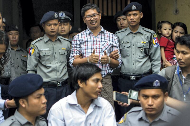Detained Myanmar journalists Kyaw Soe Oo (C-front) and Wa Lone (C-back) are escorted by after appearing before a court trial in Yangon on August 20, 2018. - At the time of their arrest Kyaw Soe Oo, 28 and Wa Lone, 32, had been investigating the massacre of 10 Rohingya Muslims in Rakhine a week after militants attacked police posts on August 25, 2017 triggering a brutal response from police and troops. (Photo by YE AUNG THU / AFP)