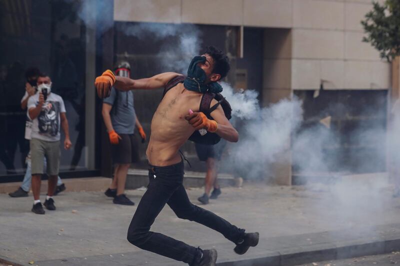 An anti-government protester throws a stone towards riot police during a protest near Parliament Square. AP