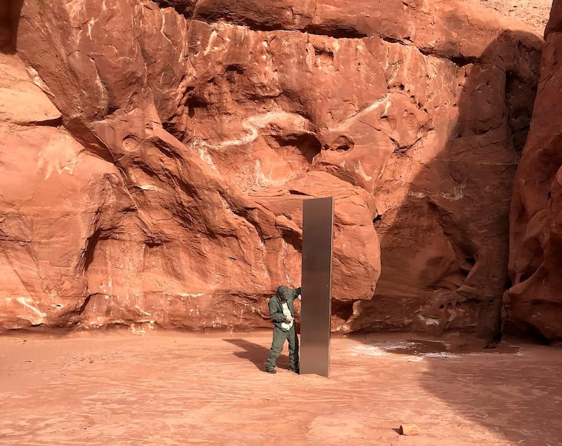 A Utah state worker inspects a metal monolith that was found installed in the ground in a remote area of red rock in Utah. Utah Department of Public Safety / AP