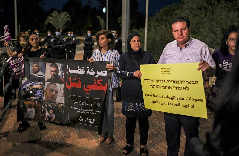 Ayman Odeh (R), leader of Israel's predominantly Arab Joint List electoral alliance and its constituent Hadash Party, holds a sign reading in Arabic and Hebrew "Empty promises.  Our children are being buried.  We do not want more! We are change", during a protest against the government's insufficient action towards rising violence levels within the Arab community, outside the home of Public Security Minister Omer Bar-Lev in the northern Israeli town of Kokhav Yair. AFP