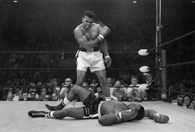 FILE - In this May 25, 1965 file photo, heavyweight champion Muhammad Ali stands over fallen challenger Sonny Liston, shouting and gesturing shortly after dropping Liston with a short hard right to the jaw, in Lewiston, Maine. The bout lasted only one minute into the first round. Ali is the only man ever to win the world heavyweight boxing championship three times. He also won a gold medal in the light-heavyweight division at the 1960 Summer Olympic Games in Rome as a member of the U.S. Olympic boxing team. In 1964 he dropped the name Cassius Clay and adopted the Muslim name Muhammad Ali. (AP Photo/John Rooney, File)