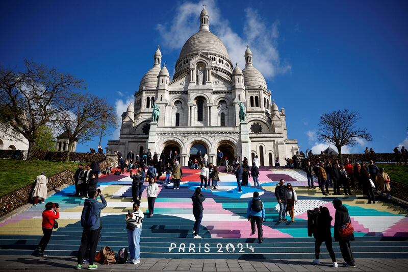 Tourists stand on the Sacre-Coeur Basilica stairs painted with the Paris 2024 Olympic and Paralympic Games colours. Reuters