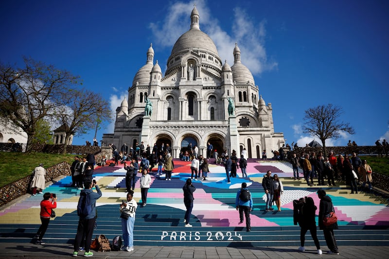 Tourists stand on the Sacre-Coeur Basilica stairs painted with the Paris 2024 Olympic and Paralympic Games colours. Reuters