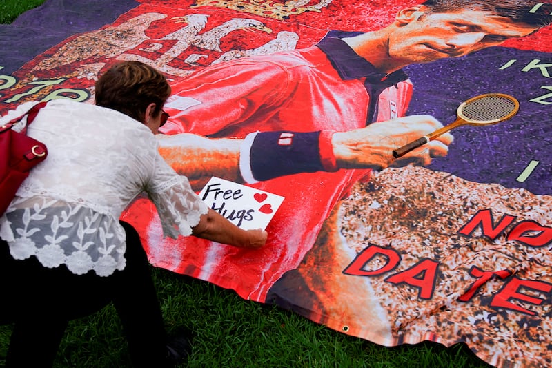 A woman places a "Free hugs" sign on a banner of Novak Djokovic outside the Park Hotel in Melbourne. Reuters