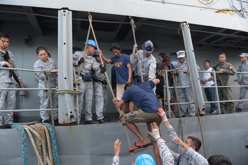 FILE - In this  June 14, 2019, file photo, rescued Filipino fishermen are transferred to another ship as they head back to shore in Occidental Mindoro province, Philippines, after sinking of their fishing boat by a Chinese trawler in the South China Sea. In a meeting of the Association of Southeast Asian Nations' defense chiefs, Philippine Defense Secretary Delfin Lorenzana thanked the Vietnamese captain whose boat rescued the 22 Filipino fishermen. (AP Photo, File)