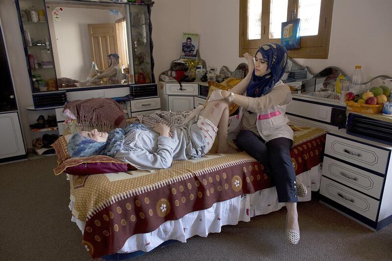 Wounded Palestinian woman Amal el Rafati,30, in the bedroom of her home in Jabalya ,Gaza October 28,2014 as she receives rehabilitation treatment from a nurse from the Palestinian Medical Relief Society in Gaza,October 28,2014 . She was seriously wounded and her husband and three year-old daughter were amongst the 16 Palestinian killed that were taking shelter at the facility . She suffered injuries to both her legs and neck in the attack in which evidence claims was by Israeli military artillery shelling . Heidi Levine for The National