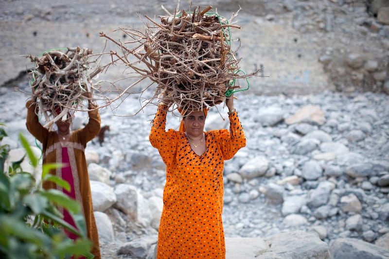 Kumzar, Oman - November 15 2012 - Two women return from collecting firewood in the village of Kumzar, Oman. Located in the northernmost tip of Oman, Kumzar is an isolated village in the Musandam peninsula. Because of its' unique geographical location, locals speak a unique non-semitic language known as Kumzari.  All inhabitants on the island also share the same last name. (Razan Alzayani / The National) 