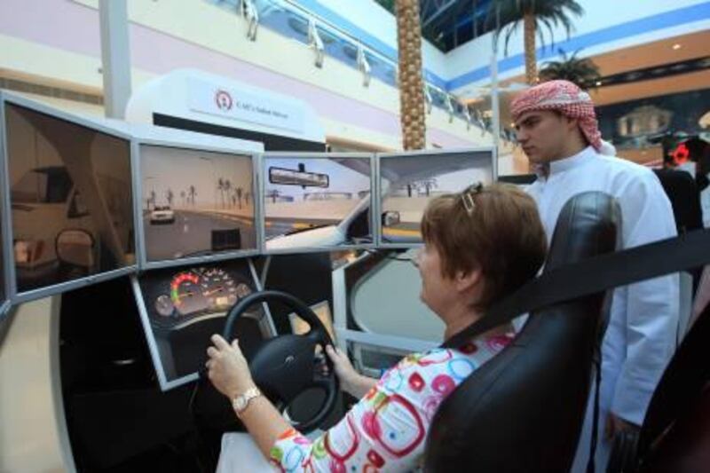 ABU DHABI - 13MAR2011 -  Visitors test their driving skills on a stimulator installed by Emirates driving company on the Opening day of the 27th GCC traffic week yesterday at Marina mall in Abu Dhabi. Ravindranath K / The National 