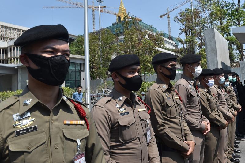 Police wearing facemasks, amid concerns over the spread of the COVID-19 novel coronavirus, stand guard outside the parliament building, currently under construction, as people take part in a demonstration calling for the creation of a new constitution in Bangkok on March 13, 2020. / AFP / Romeo GACAD
