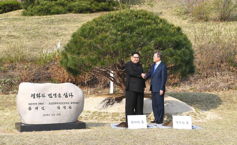 South Korean president Moon Jae-in, right, and North Korean leader Kim Jong-un shake hands after tending to a pine tree in the Demilitarised Zone in Paju, South Korea. Korea Summit Press / EPA