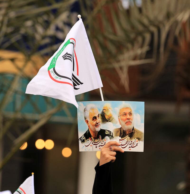 A PMF follower carries a picture of Suleimani and Al Muhandis. EPA