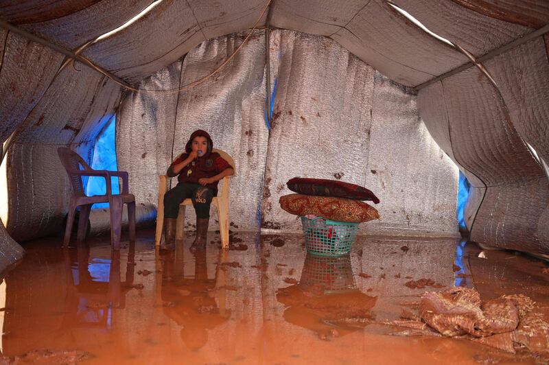 A Syrian boy sits in a water logged tent at the Cordoba camp for internally displaced Persons (IDP), close to Batabu town, along the highway leading to the Syrian Bab al-Hawa border crossing with Turkey, in the northern Syrian Idlib province. Following heavy rain storms, the camp has become water logged, flooding the tents and making the the roads muddy and difficult to maneuvre on.  AFP