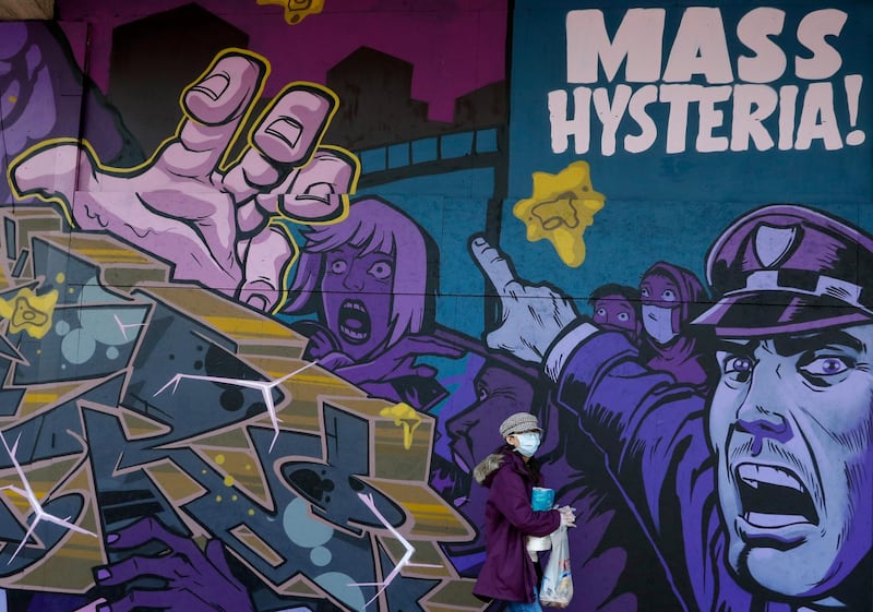 A pedestrian, wearing a protective mask, walks past a street art mural, depicting "Mass Hysteria" related to the Covid-19 pandemic, in Birmingham, U.K., on Monday, April 6, 2020. Telecom masts that enable the next generation of wireless communication were set on fire in the U.K. in recent days, apparently by people motivated by a theory that the tech helps spread the coronavirus. Photographer: Darren Staples/Bloomberg