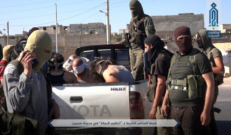 This Sunday, July 9, 2017 photo, released by Ibaa news agency, the communications arm of the al Qaeda-linked Levant Liberation Committee, outlet that is consistent with independent AP reporting, shows al-Qaida-linked fighters after they detained alleged members of the Islamic State group in the northwestern Syrian village of Sarmin in Idlib province. Syrian rebels and opposition activists say an al-Qaida-linked group is on the verge of snuffing out what remains of the 2011 Syrian uprising against President Bashar Assad in northwest Syria. Arabic reads, "Detaining members of the Islamic State group in the city of Sarmin." (Ibaa News Agency, via AP)