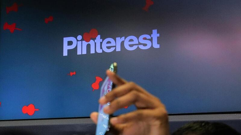 A guest holds up a phone during the Pinterest IPO on the floor of the New York Stock Exchange on April 18, last year. Reuters