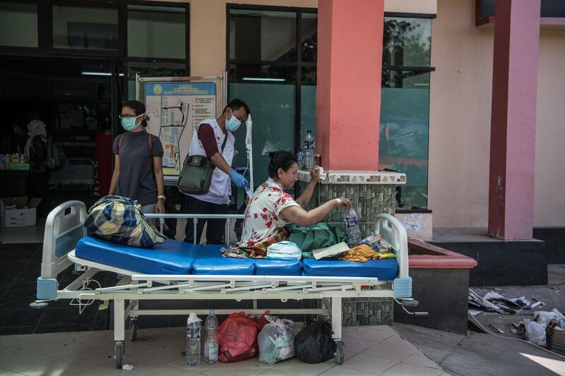 An injured woman sits on a stretcher outside a hospital in Palu. Getty Images