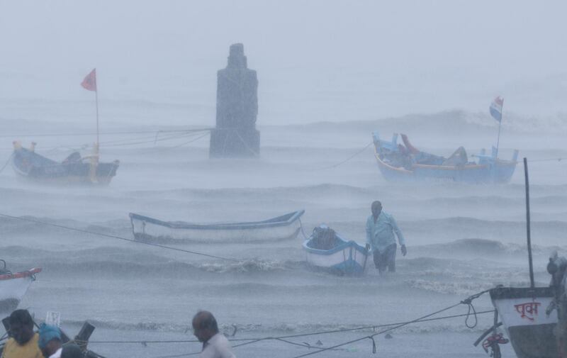 A fisherman waits for help as he tries to move a fishing boat to a safer ground on the Arabian Sea coast in Mumbai, India, Monday, May 17, 2021. Cyclone Tauktae, roaring in the Arabian Sea was moving toward India's western coast on Monday as authorities tried to evacuate hundreds of thousands of people and suspended COVID-19 vaccinations in one state. (AP Photo/Rafiq Maqbool)