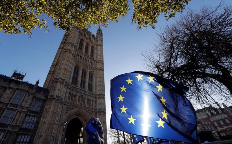 FILE - In this Jan. 22, 2019, file photo, the sun shines through European Union flags tied to railings outside parliament in London. The prospect of restoring a hard border between Ireland and Northern Ireland once Britain leaves the EU has raised fears or a return to the old reality where British army checkpoints, shootings, bombings and gun-smuggling were the norm. (AP Photo/Kirsty Wigglesworth, File)