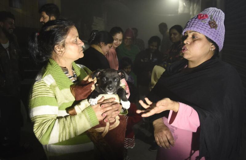 Residents - one holding a puppy-  speak on a street in Amritsar late February 12, 2021, after leaving their homes as tremors shook the city in Punjab State north-western India following a powerful earthquake in Tajikistan of a magnitude of 5.9 according to the United States Geological Survey (USGS).  / AFP / NARINDER NANU
