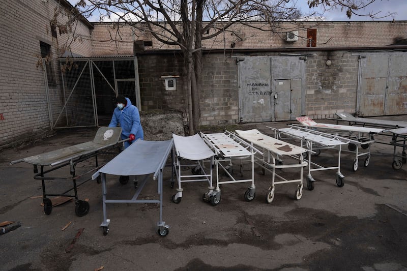 A mortuary worker wheels a stretcher used to move dead bodies before they are buried on the outskirts of Mariupol. AP